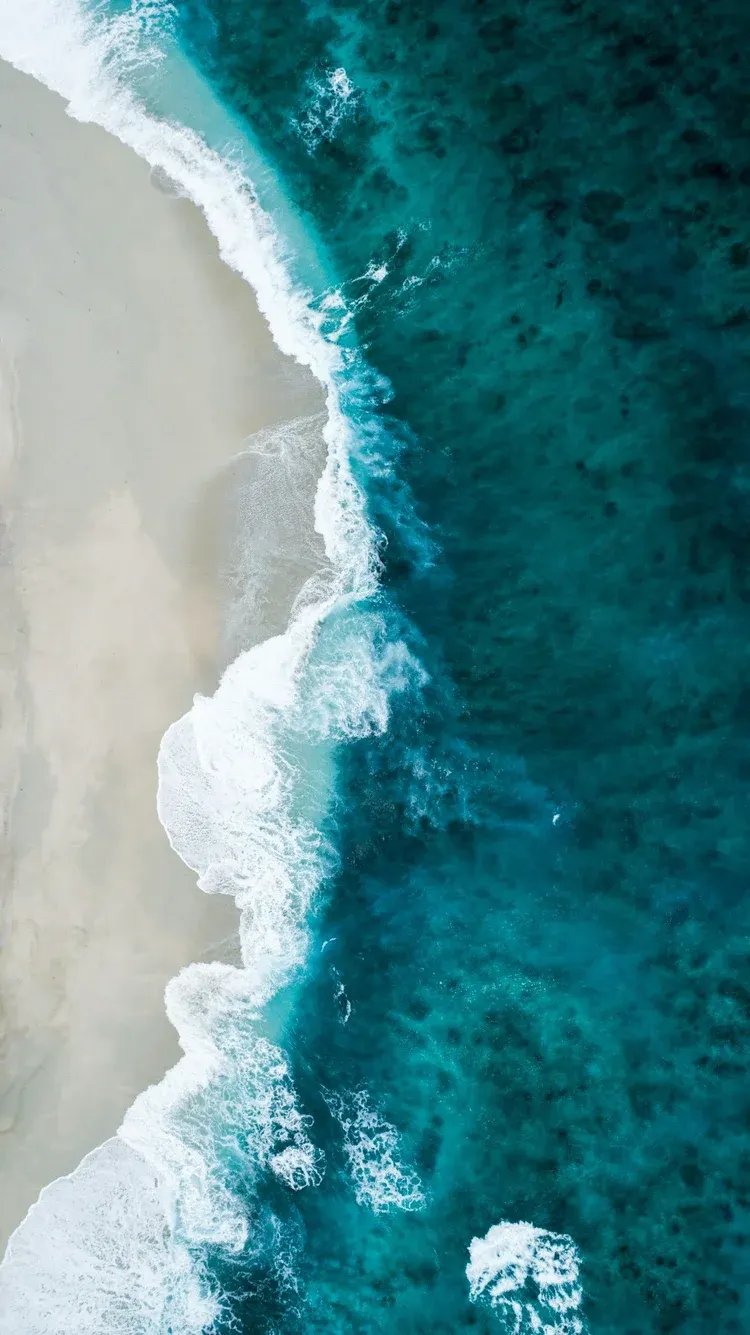 Aerial view of turquoise surf meeting a white-sand beach