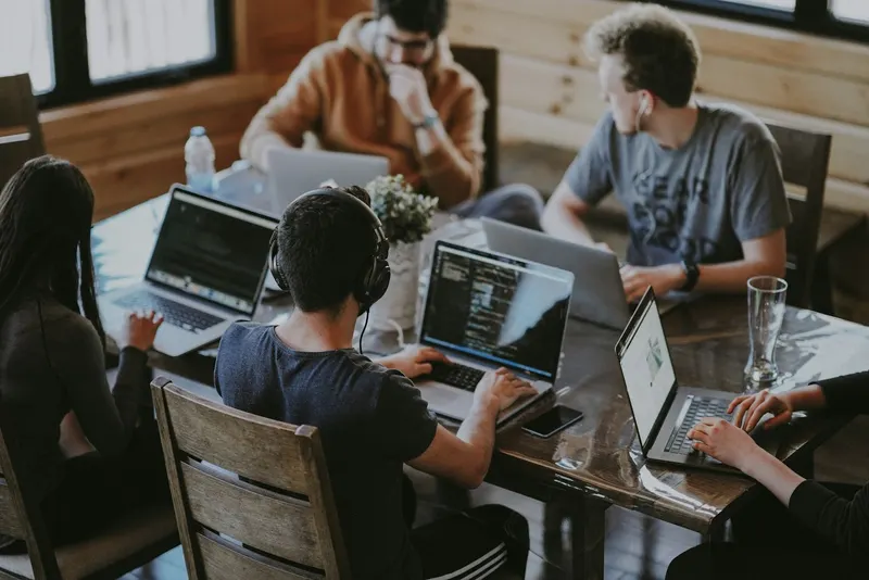 A small team working together around a long wooden table